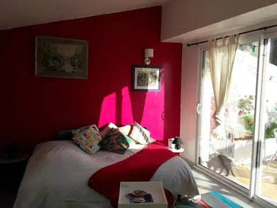 a bedroom with red walls and a bed with a window at Le studio perché in Carcassonne