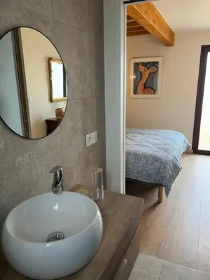 a bathroom with a sink and a mirror and a bed at Escapade au Somail in Le Somail