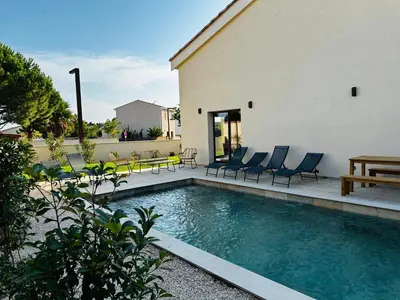 a swimming pool with chairs and a table next to a building at Escapade au Somail in Le Somail
