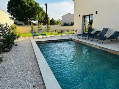 a swimming pool with chairs and a table next to a house at Escapade au Somail in Le Somail
