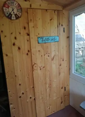 a wall in a cabin with a clock on it at La Succulente Vivace in Cambounès