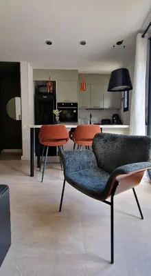 a living room with two chairs and a kitchen at Entrez en lice, Face à la Cité vue sublime in Carcassonne