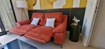 an orange couch with two pillows in a living room at Entrez en lice, Face à la Cité vue sublime in Carcassonne
