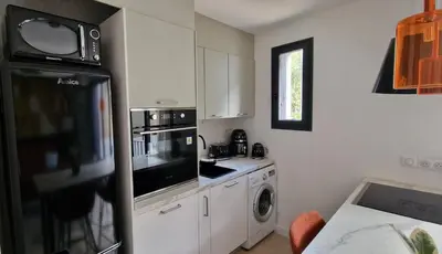 a kitchen with white cabinets and a black refrigerator at Entrez en lice, Face à la Cité vue sublime in Carcassonne