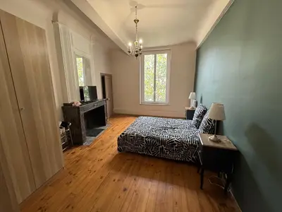 a living room with a bed and a couch and a window at La paisible, coeur de ville Narbonne in Narbonne