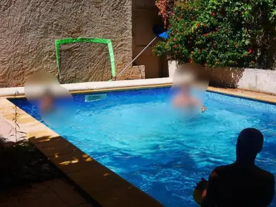 two people sitting next to a swimming pool at La paisible, coeur de ville Narbonne in Narbonne