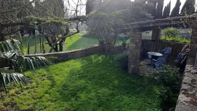 a garden with a stone wall and a chair at Le Petit Coeur de Cassaignes in Cassaignes