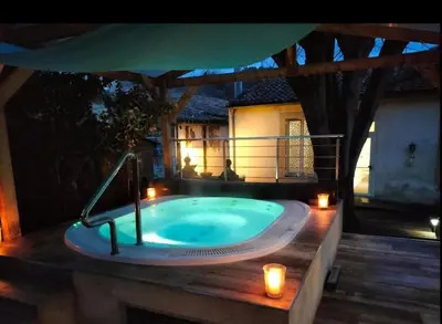 a jacuzzi tub on a deck with candles at Le Petit Coeur de Cassaignes in Cassaignes