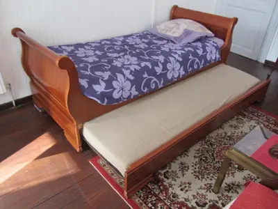 a bed in a room with a rug and a table at Aude Cité-City in Carcassonne