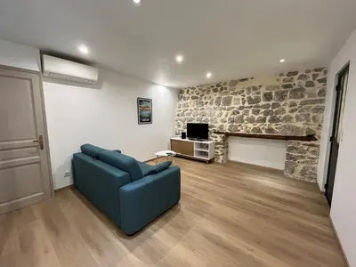 a living room with a blue couch and a stone wall at Maison Gruissan village in Gruissan