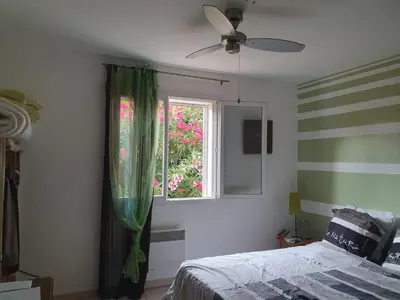 a bedroom with a bed and a window with green curtains at Villa de l Ode in Mirepeisset