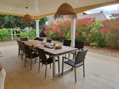 a wooden table and chairs on a patio with flowers at Villa de l Ode in Mirepeisset
