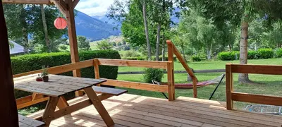 a wooden deck with a table and a hammock at grote lodge safaritent 4 in Camurac