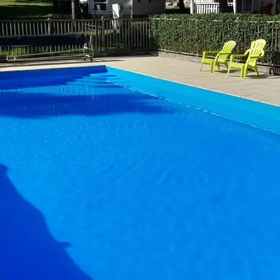 a blue swimming pool with two yellow chairs next to it at grote lodge safaritent 4 in Camurac