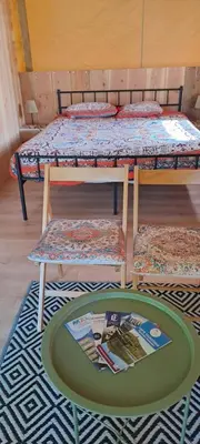 a room with two bunk beds and a table with a magazine at grote lodge safaritent 4 in Camurac
