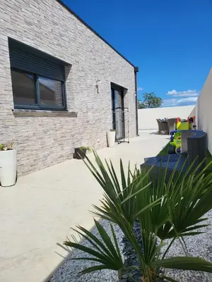 a brick house with a palm tree in front of it at Villa moderne avec Piscine et cuisine extérieure in Saint-Nazaire-dʼAude