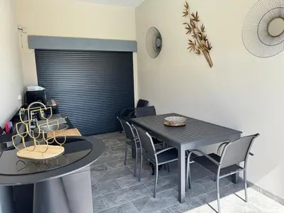 a dining room with a black table and chairs at Villa moderne avec Piscine et cuisine extérieure in Saint-Nazaire-dʼAude