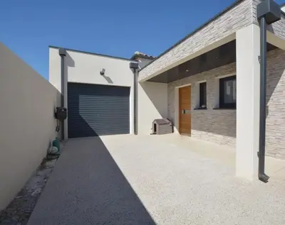 a garage with a garage door on the side of a house at Villa moderne avec Piscine et cuisine extérieure in Saint-Nazaire-dʼAude