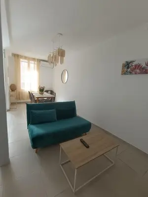 a living room with a green couch and a coffee table at Cocon lumineux avec cour privée in Salses-le-Chateau