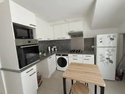 a kitchen with white appliances and a wooden table at Cocon lumineux avec cour privée in Salses-le-Chateau