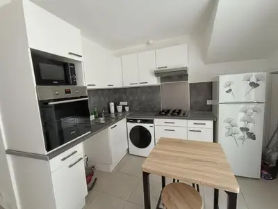 a kitchen with white appliances and a wooden table at Cocon lumineux avec cour privée in Salses-le-Chateau