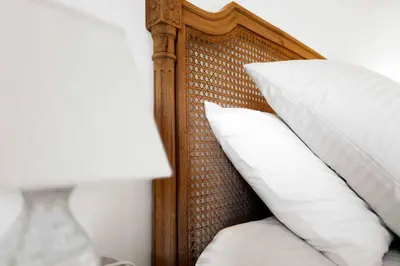 a bed with a wooden head board with white pillows at Le Tranquille characterful apartment in Carcassonne