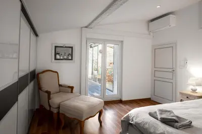 a bedroom with a bed and a chair and a window at Le Tranquille characterful apartment in Carcassonne