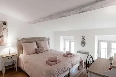 a white bedroom with a large bed with pink pillows at Le Tranquille characterful apartment in Carcassonne