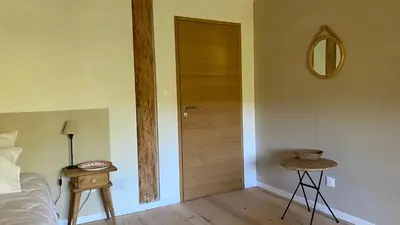 a bedroom with a door and a table and a bed at Chambre confortable à la campagne in Dun