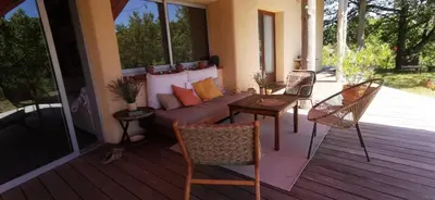 a porch with a couch and chairs on a deck at Chambre confortable à la campagne in Dun