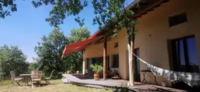 a porch of a house with a table and chairs at Chambre confortable à la campagne in Dun