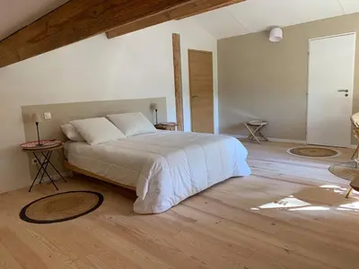 a bedroom with a large bed and a wooden floor at Chambre confortable à la campagne in Dun