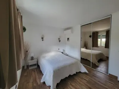 a white bedroom with a mirror and a bed at Villa piscine privée in Capestang