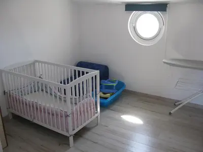 a white crib in a room with a window at Douce Parenthèse - Maison de Vacances - 8 pers - Terrasse in Lapalme