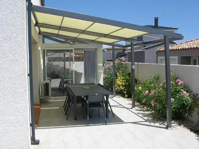 a patio with a table and chairs under a pergola at Douce Parenthèse - Maison de Vacances - 8 pers - Terrasse in Lapalme