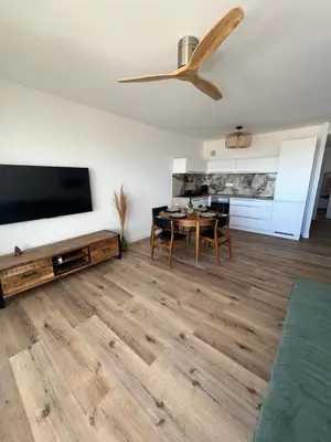 a living room with a table and a flat screen tv at APPARTEMENT Rénové de type 3 VUE MER in Port-la-Nouvelle