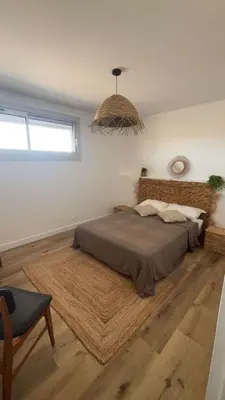 a bedroom with a large bed and a chandelier at APPARTEMENT Rénové de type 3 VUE MER in Port-la-Nouvelle