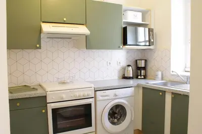 a kitchen with green cabinets and a washing machine at Chez Céline, plein centre ville in Narbonne