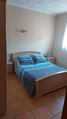 a bedroom with a bed with blue blankets and pillows at Charmant T2 à 5min des plages in Port-la-Nouvelle
