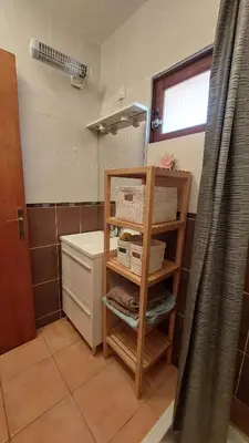 a bathroom with a toilet and a shelf with towels at Charmant T2 à 5min des plages in Port-la-Nouvelle