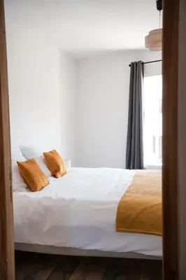 a bedroom with a bed with white sheets and orange pillows at Hygge en Méditerranée in Salses-le-Chateau