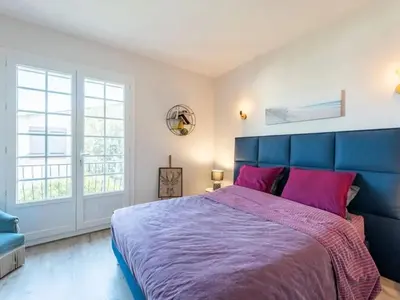 a bedroom with a large blue bed with pink pillows at Maison des Artistes - Centre Ville in Narbonne
