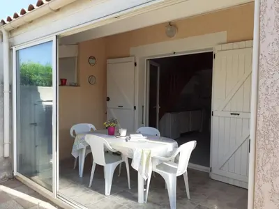 a dining room with a table and white chairs at Villa proche de la plage in Port-la-Nouvelle