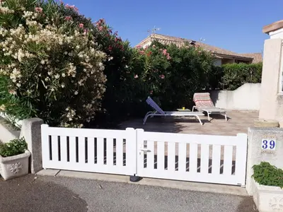 a white picket fence with two chairs and a table at Villa proche de la plage in Port-la-Nouvelle