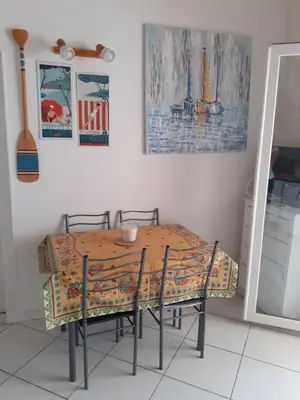 a dining room table with chairs and a table and a table at Villa proche de la plage in Port-la-Nouvelle