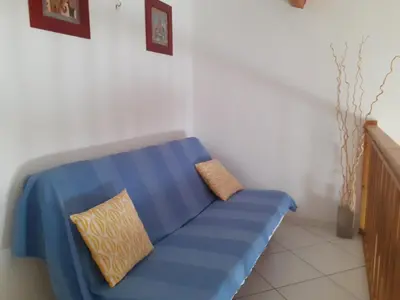 a blue couch with two pillows on it in a room at Villa proche de la plage in Port-la-Nouvelle