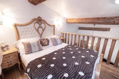 a bedroom with a large bed with a wooden headboard at Chambre romantique du Couvent in Narbonne