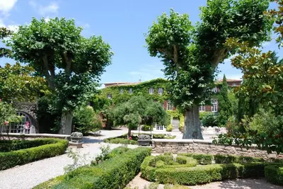 a garden with trees and bushes in front of a building at Appartement dans l'aile du château 130M2 6 personnes in Carcassonne
