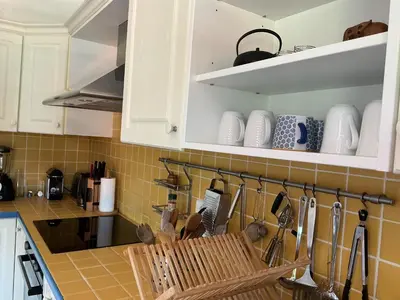 a kitchen with white cabinets and a counter top at Le Doul Jolie villa au calme climatisée grande piscine jardin in Peyriac-de-Mer