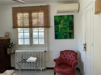 a living room with a red chair and a window at Le Doul Jolie villa au calme climatisée grande piscine jardin in Peyriac-de-Mer